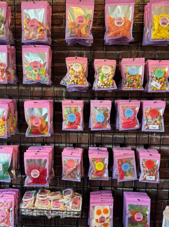 Wall display of various candy packages in pink bags with colorful candies.