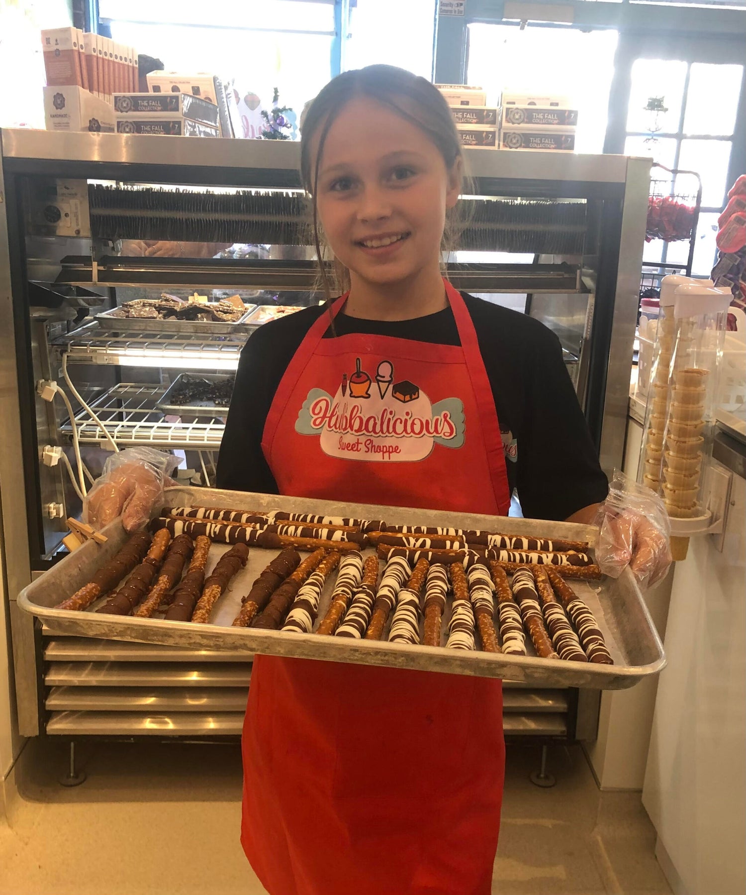 Person holding a tray of pastries in a bakery